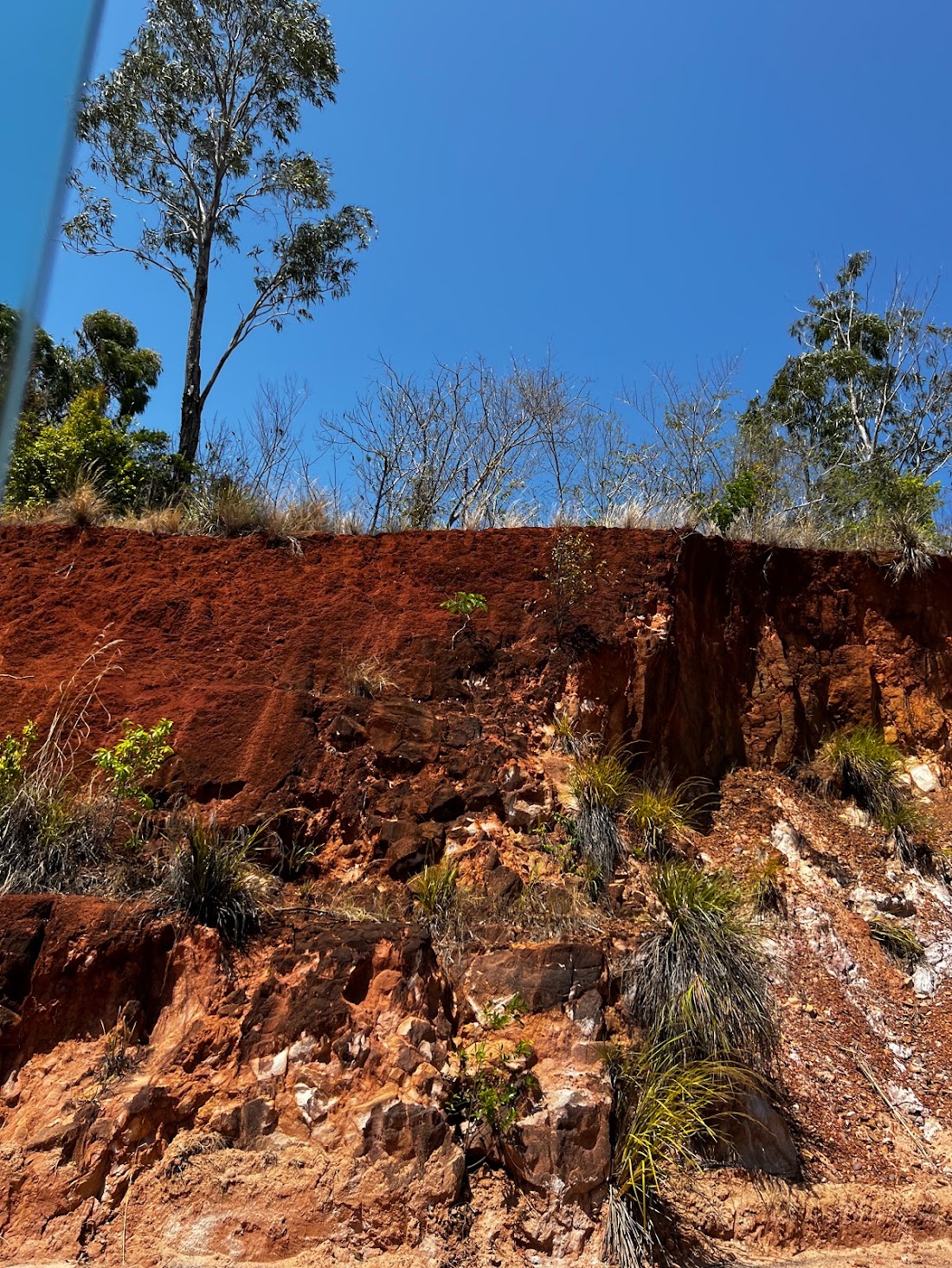 Estetica Fluida, Milano Design Week 2023: red earth bank with trees under a blue sky