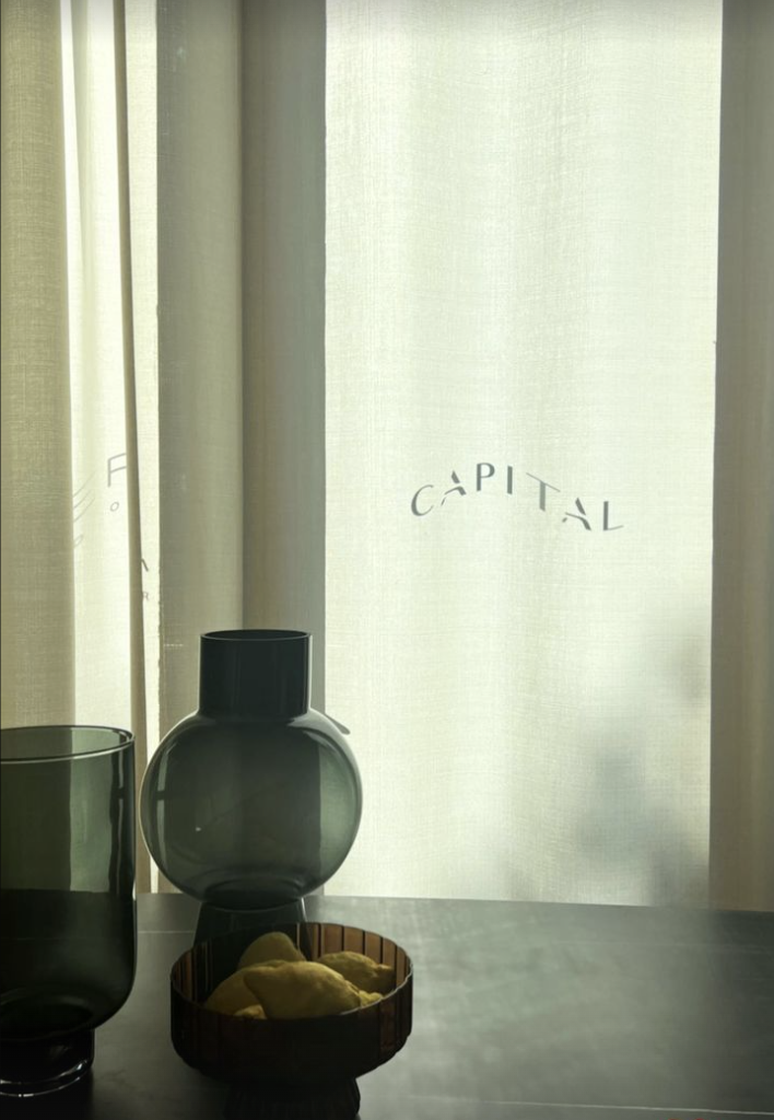 Capital Interiors showroom: the Capital logo on a sheer curtain behind dark glass vases.