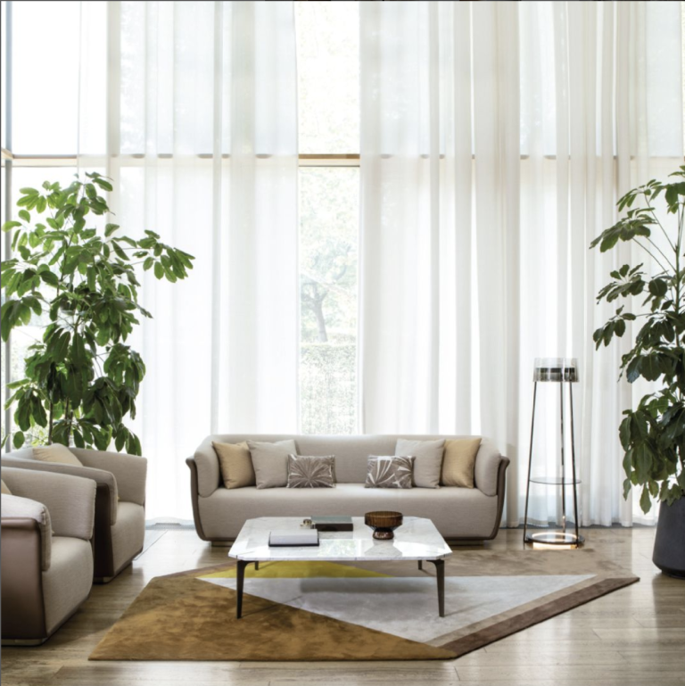 Capital Interiors showroom living area with beige sofas, armchairs, plants and sheer curtains.