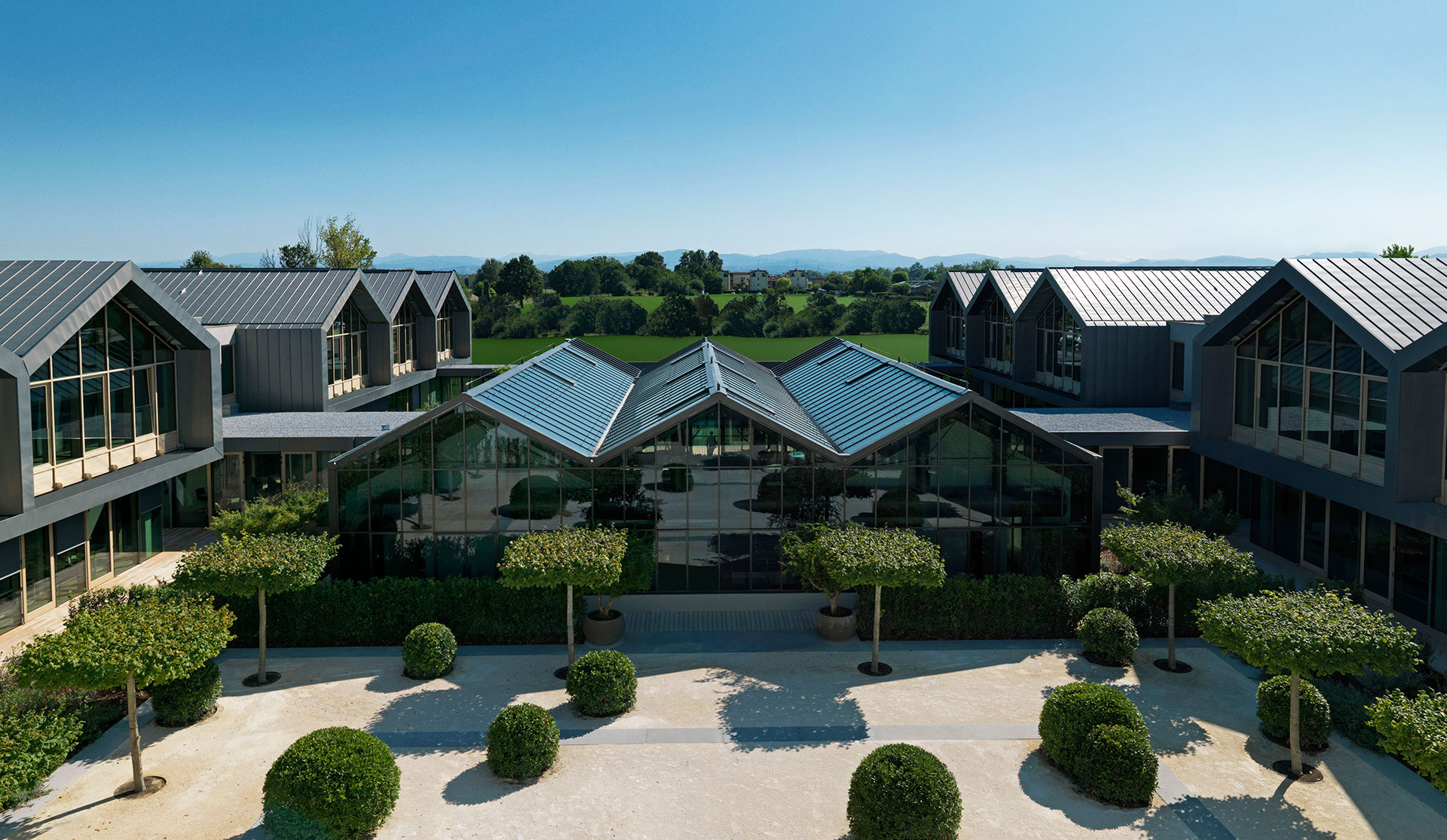 Concept for Davines Group Village: aerial view of the gabled glasshouses and clipped trees