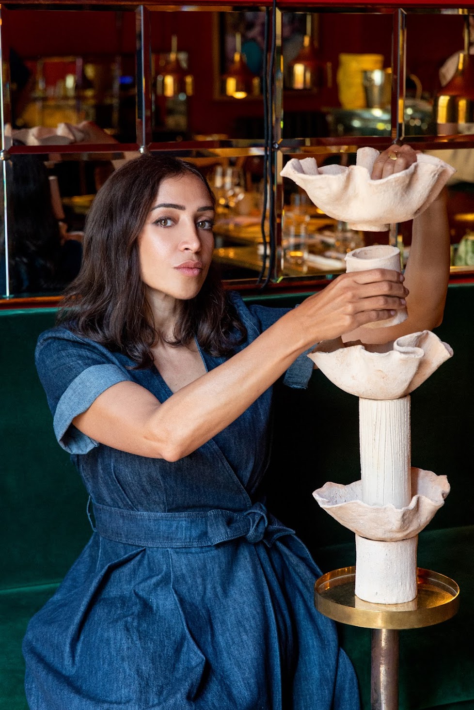 Elena Pelosi Studio: donna con abito in denim che impila bacili in ceramica su una colonna