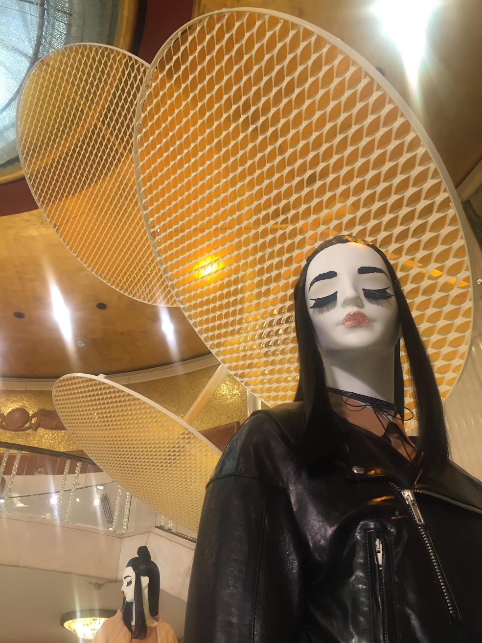 Mannequin in a black leather jacket beneath large woven-mesh discs, Zara installation for Milano Design Week.