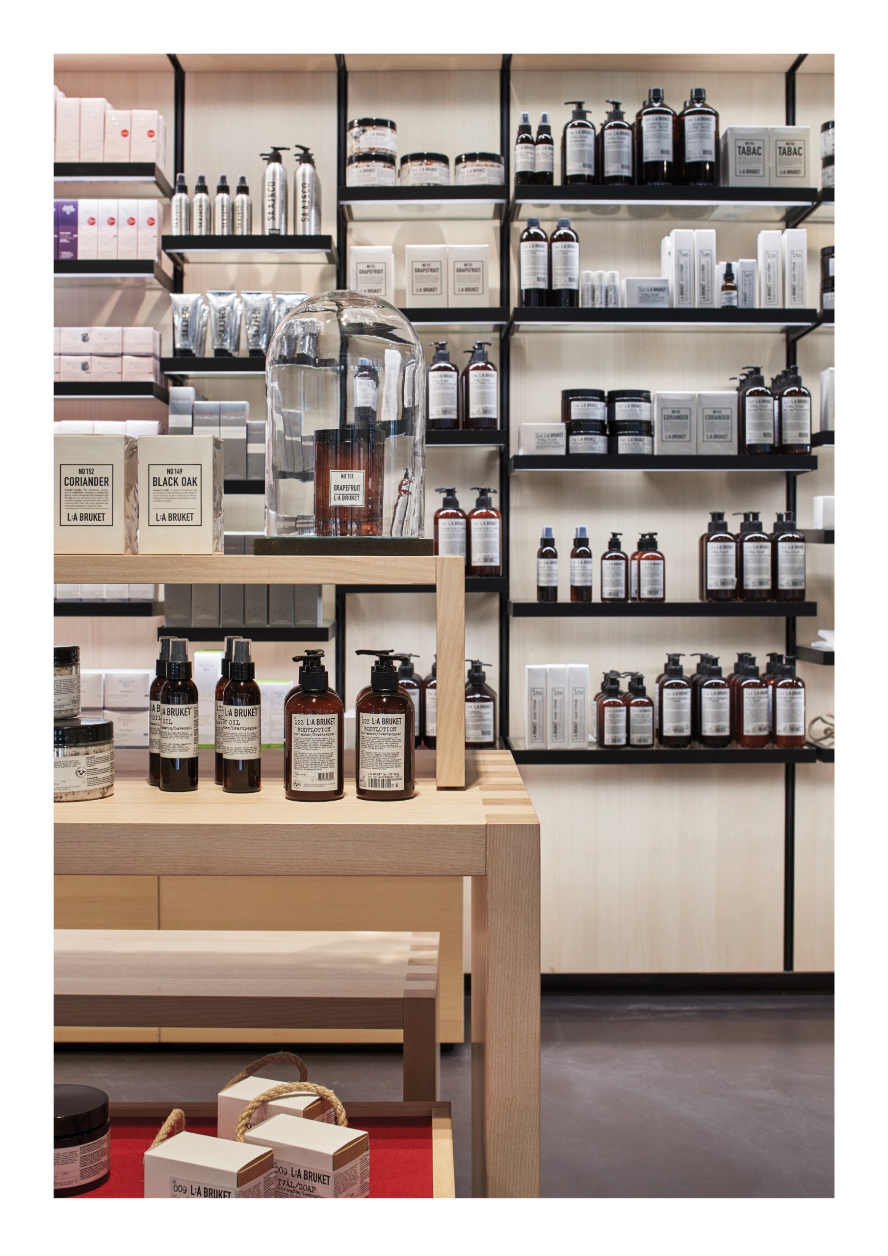 Zur Rose pharmacy interior with black metal shelving and pale wood display tables.