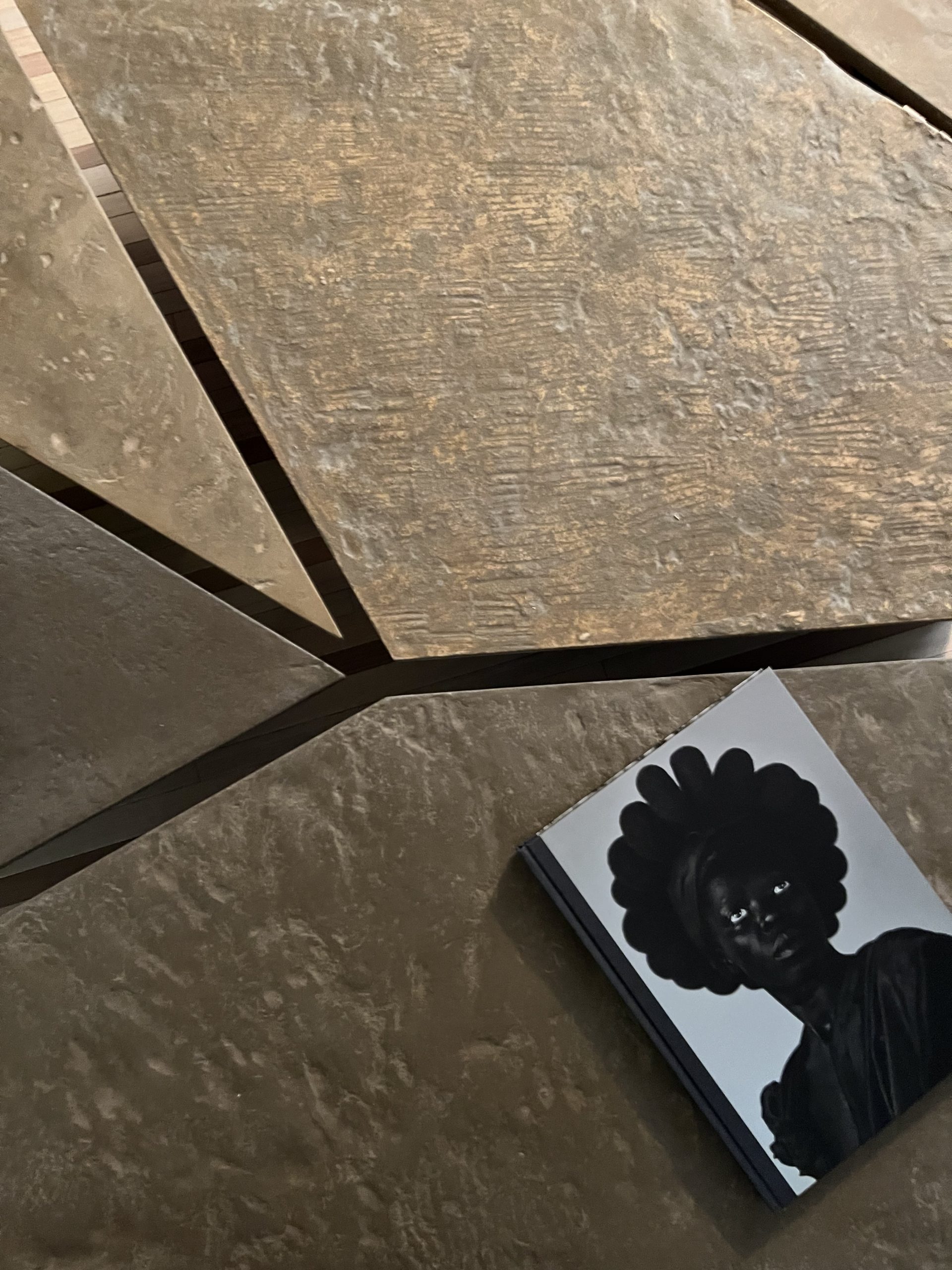 Close-up of the Kurinuki cocciopesto tops at Milano Design Week 2023, with a book resting on the surface.