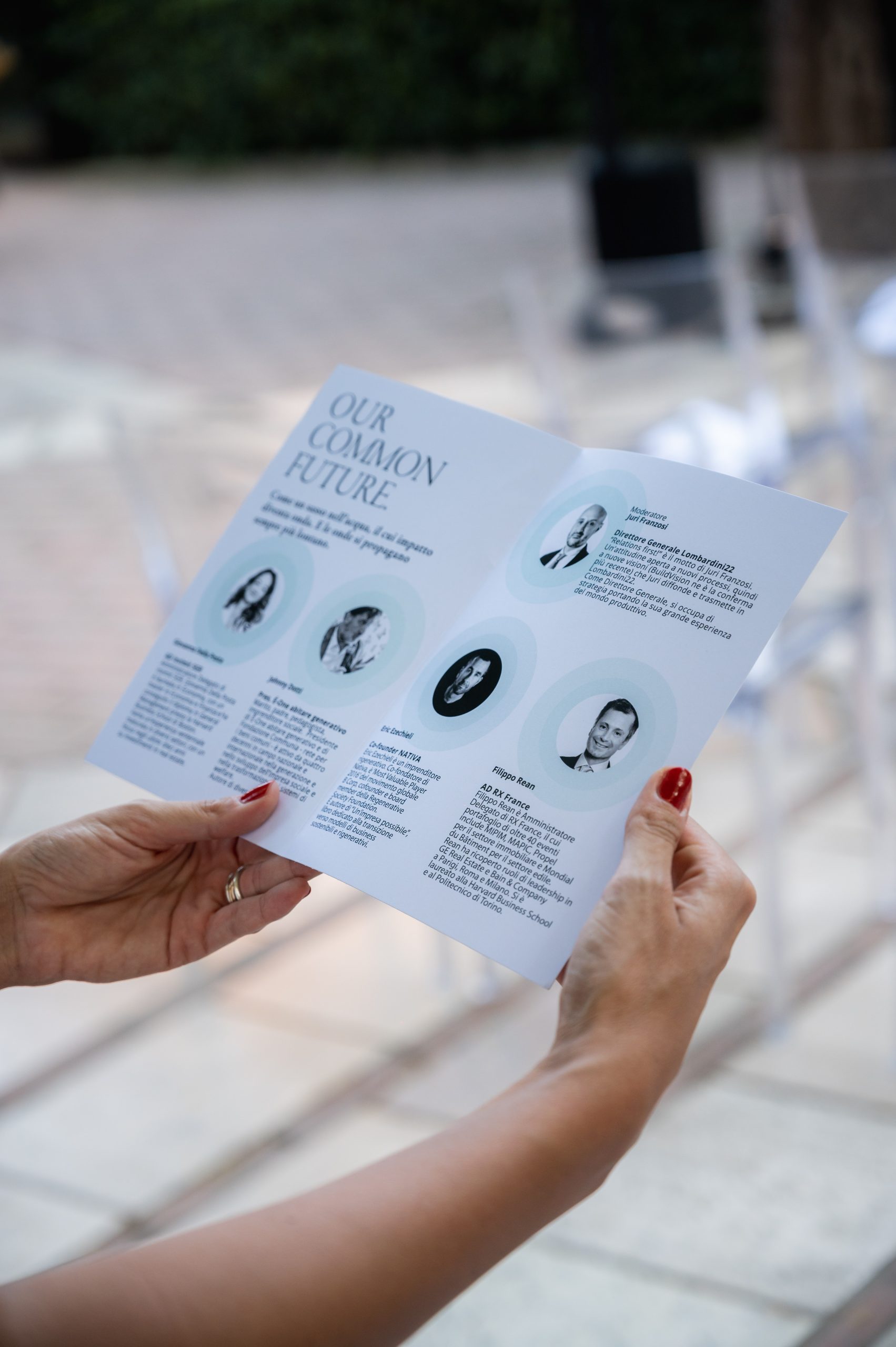 Our Common Future, Guggenheim: hands holding the event programme with speaker portraits