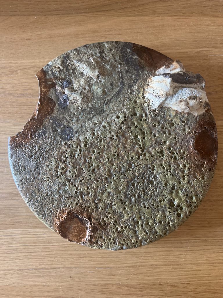 Melting Pot, Land: round porous ceramic piece on an oak surface