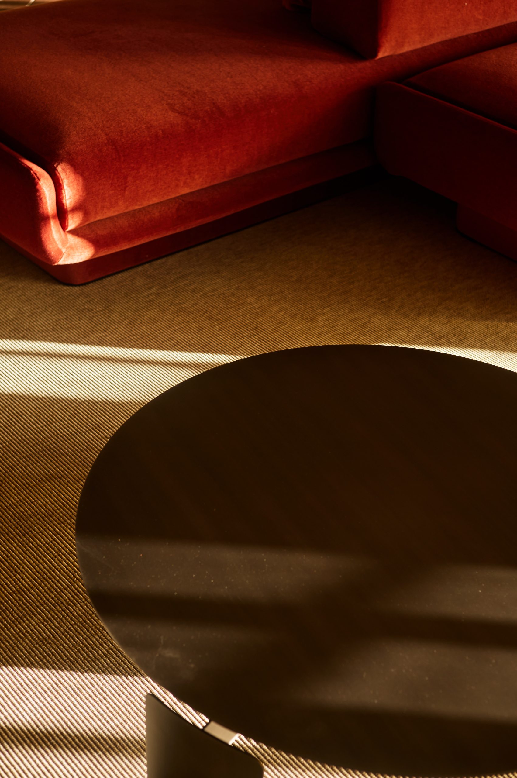 Detail of a rust velvet sofa and a dark round table in the Sala quadri, Fondazione Zegna, interior design by Elena Pelosi.