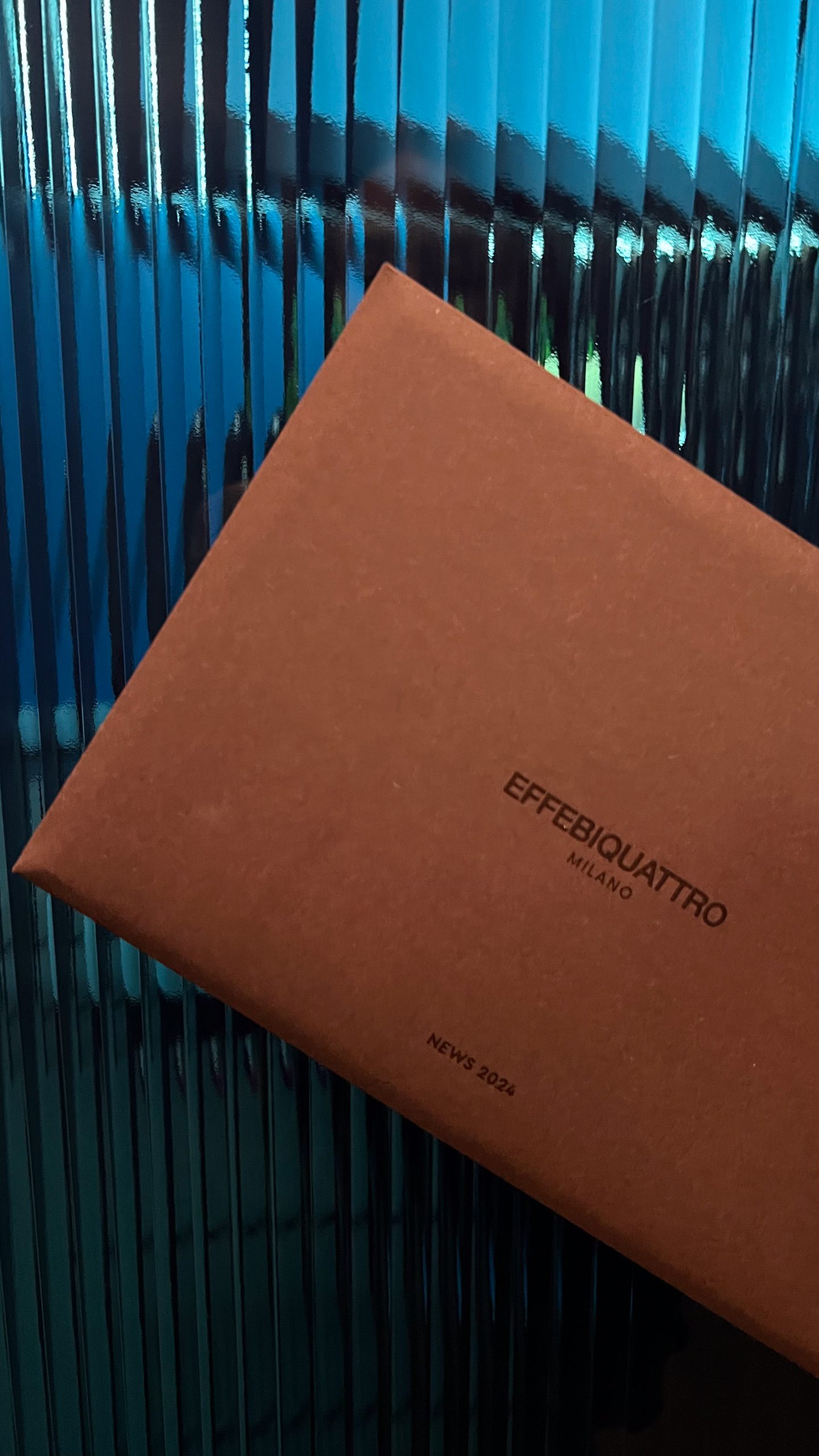Effebiquattro Milano brand image: brown box with the logo on fluted blue glass