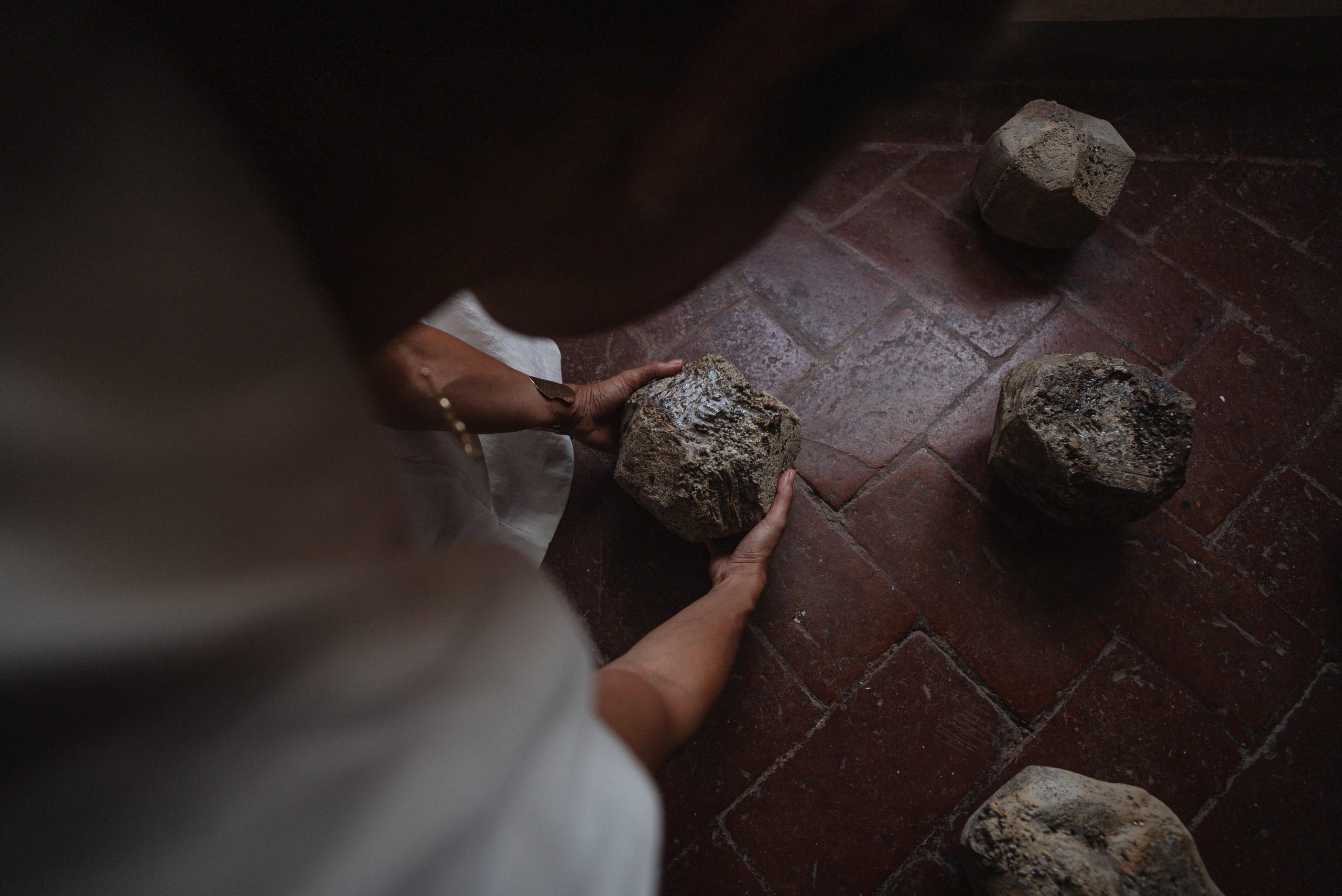 Portal of Memory performance, Villa Ferdinanda: hands placing ceramic stones on a brick floor