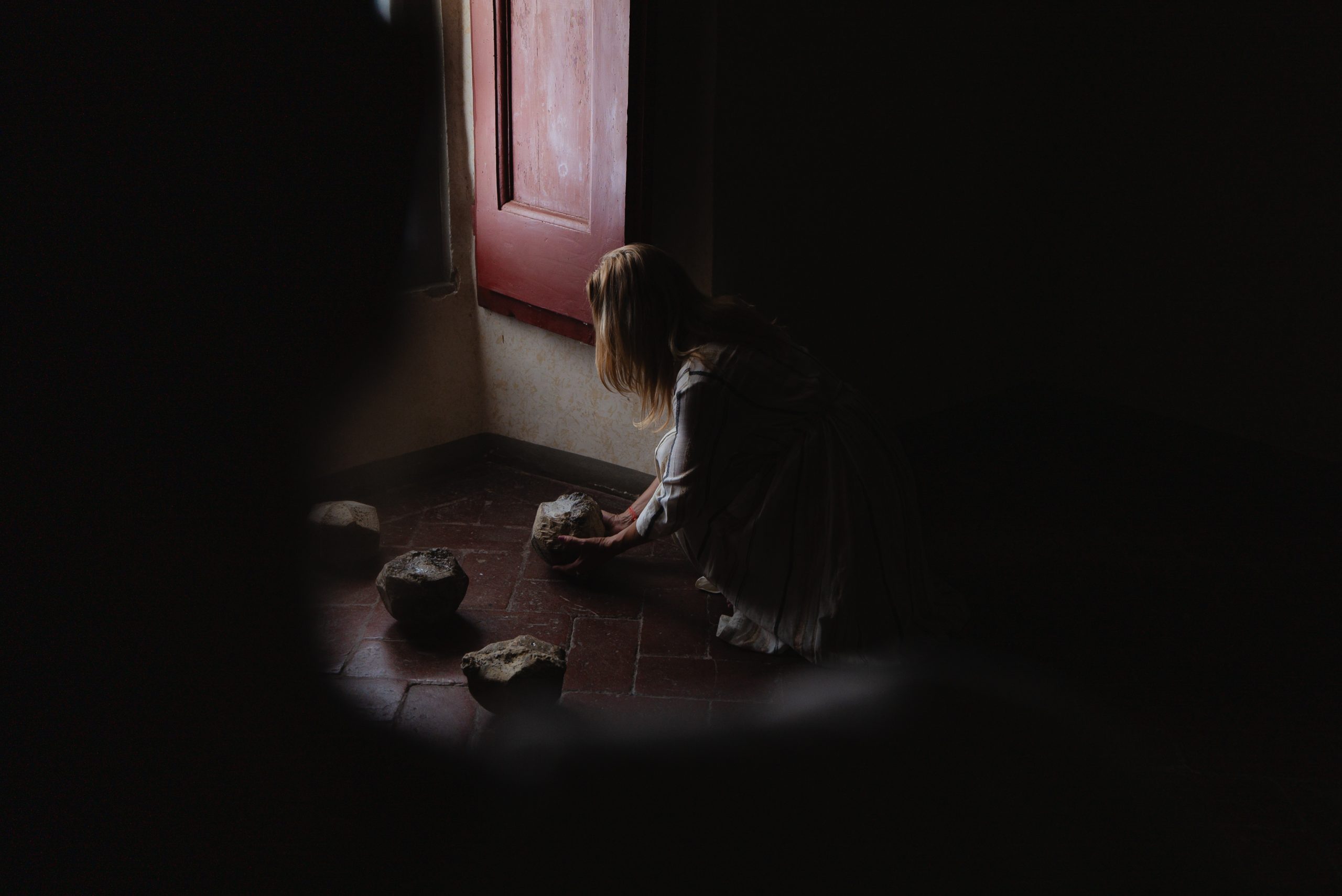 Portal of Memory performance, Villa Ferdinanda: performer among stones in a darkened room