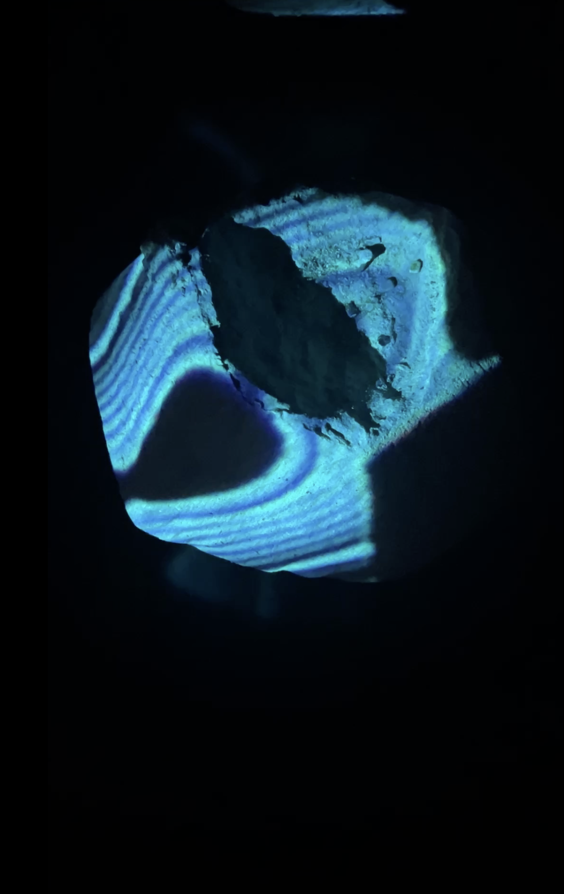 Portal of Memory: blue striped light pattern projected onto a stone in darkness