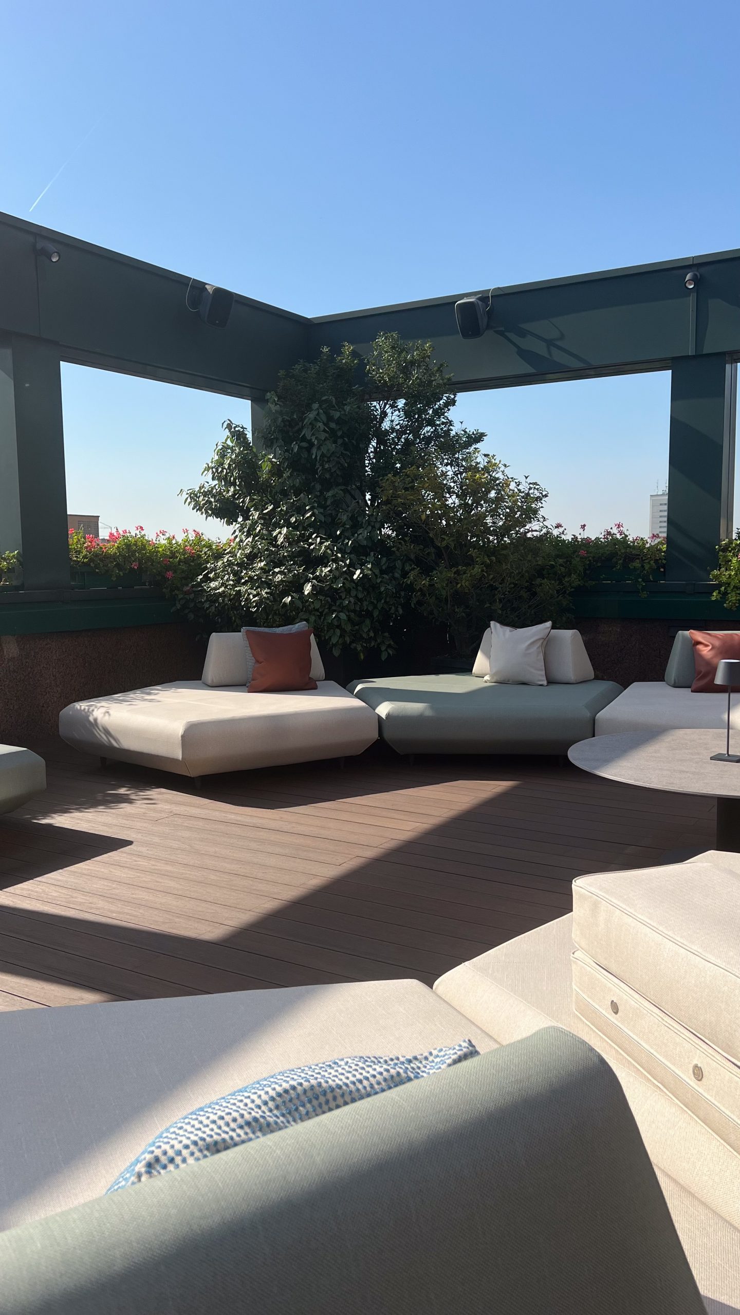 Elena Pelosi Studio: terrazza sul tetto con divani bassi bianchi e fioriere