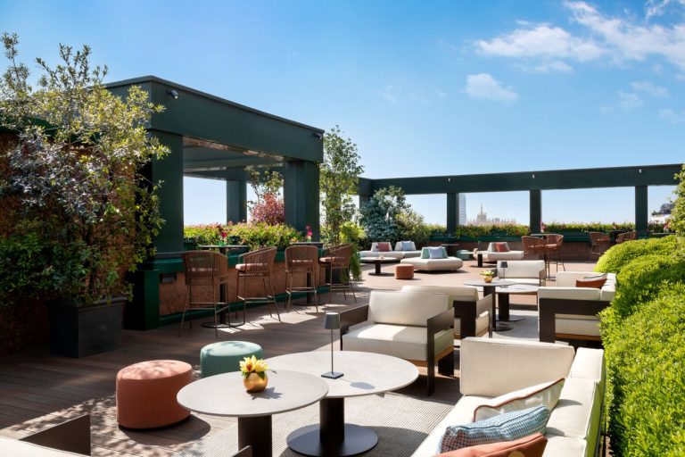 Rooftop terrace of The Westin Palace Milan with lounge seating, planters and a view over the city.