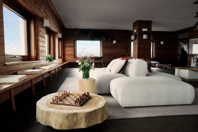 Monte Marca for Fondazione Zegna: lounge with white sofas, a log table and timber walls