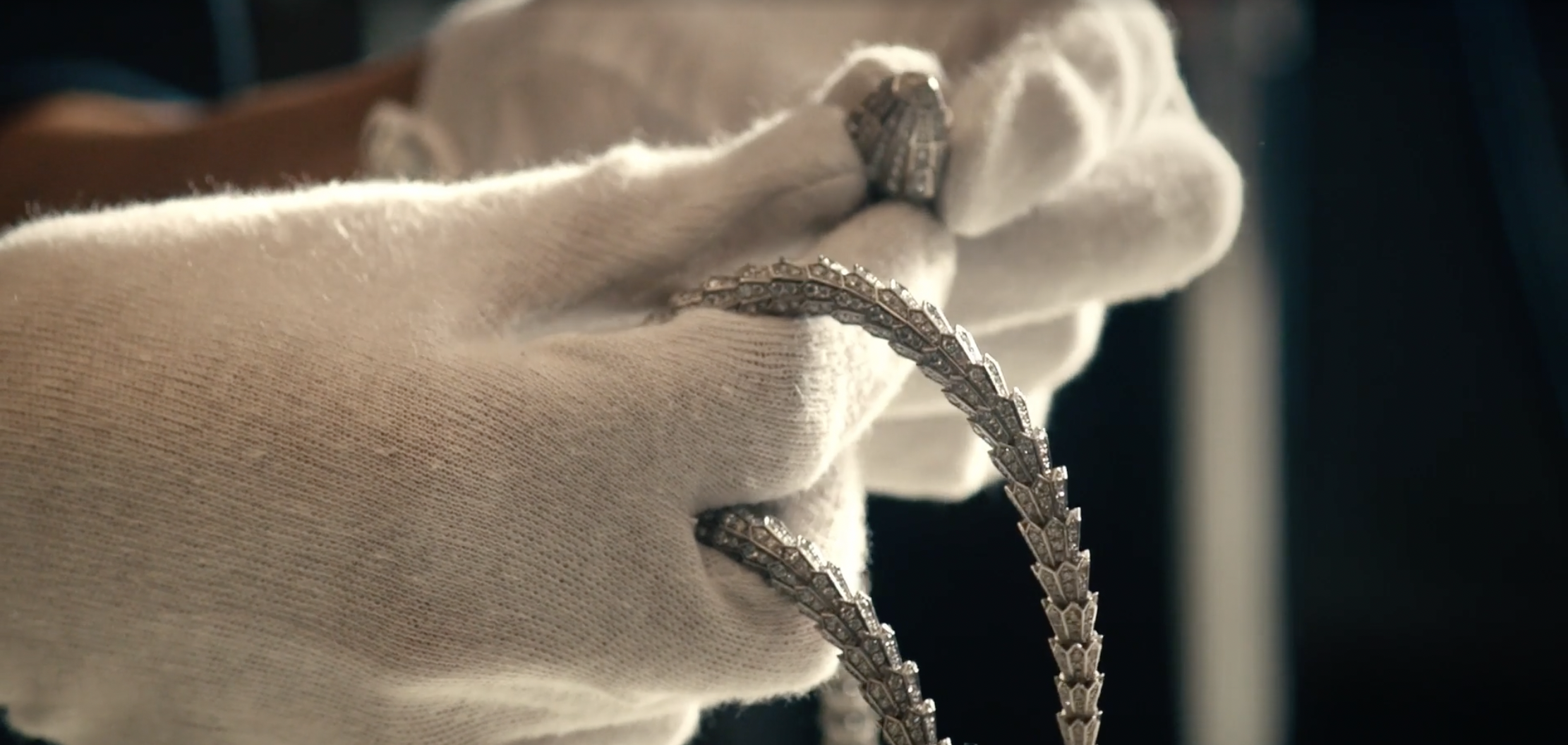 White-gloved hands holding the Bvlgari Serpenti necklace during the shoot at Fornace Curti, Milan.