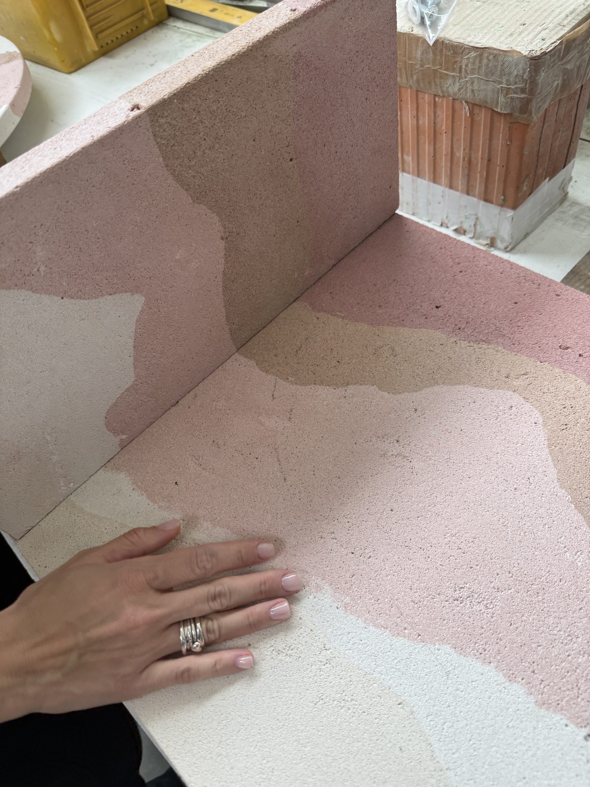 Stratigrafica collection: hand on a pink layered panel in the workshop