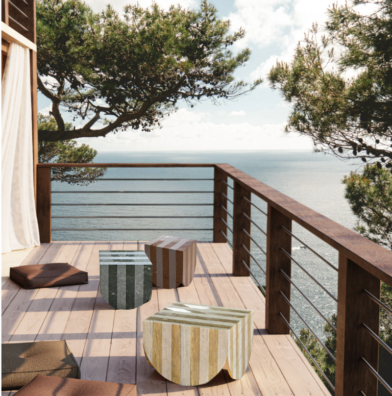 Render of Capri side tables in striped marble on a wooden terrace overlooking the sea.