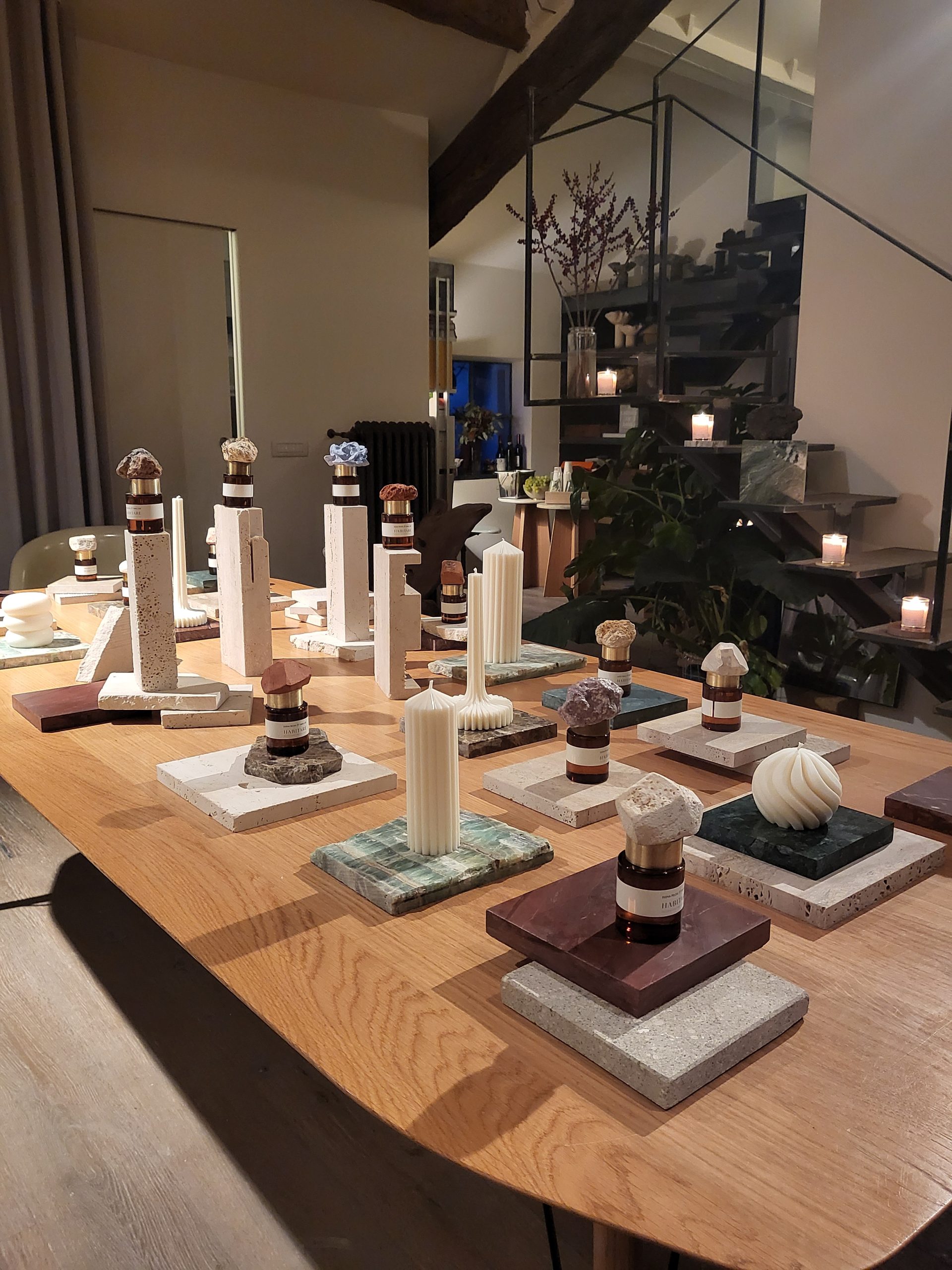 HABITARE event: long table set with bottles, candles and objects on marble tiles