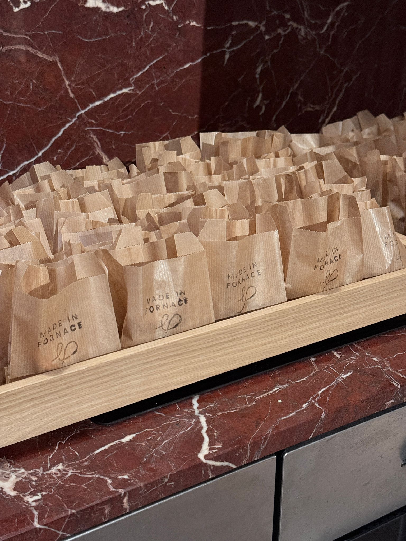 HABITARE event: rows of paper gift bags on a red marble counter