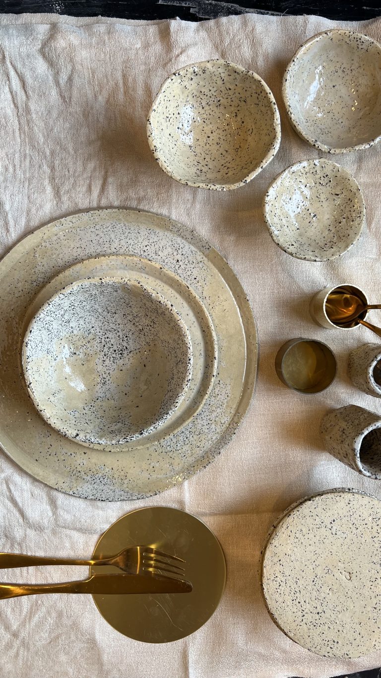 Dalmatina ceramics: speckled plates, bowls and cups on linen with brass cutlery