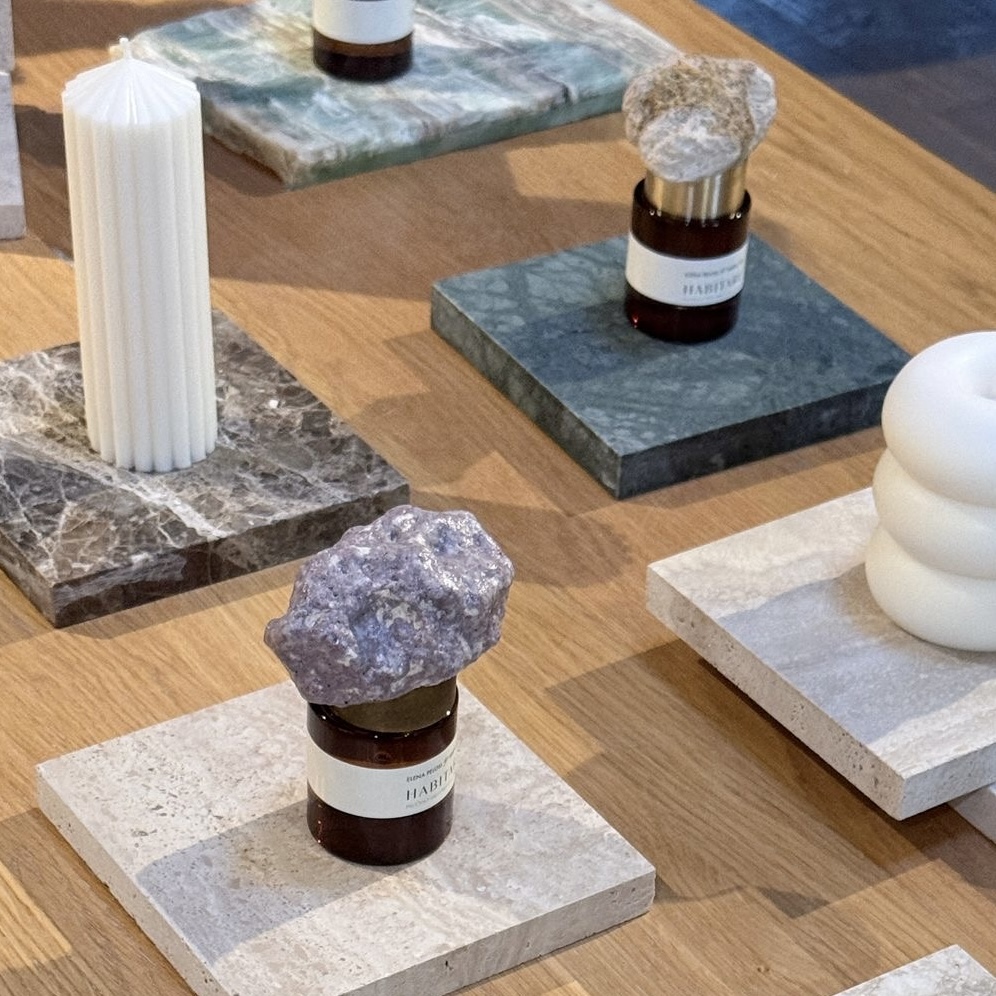 HABITARE event: fragrance bottles with stone caps and sculptural candles on marble tiles