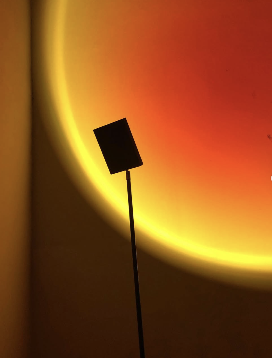 Floor lamp silhouetted against a glowing orange and yellow halo, Halo Project at Lampo Milano.