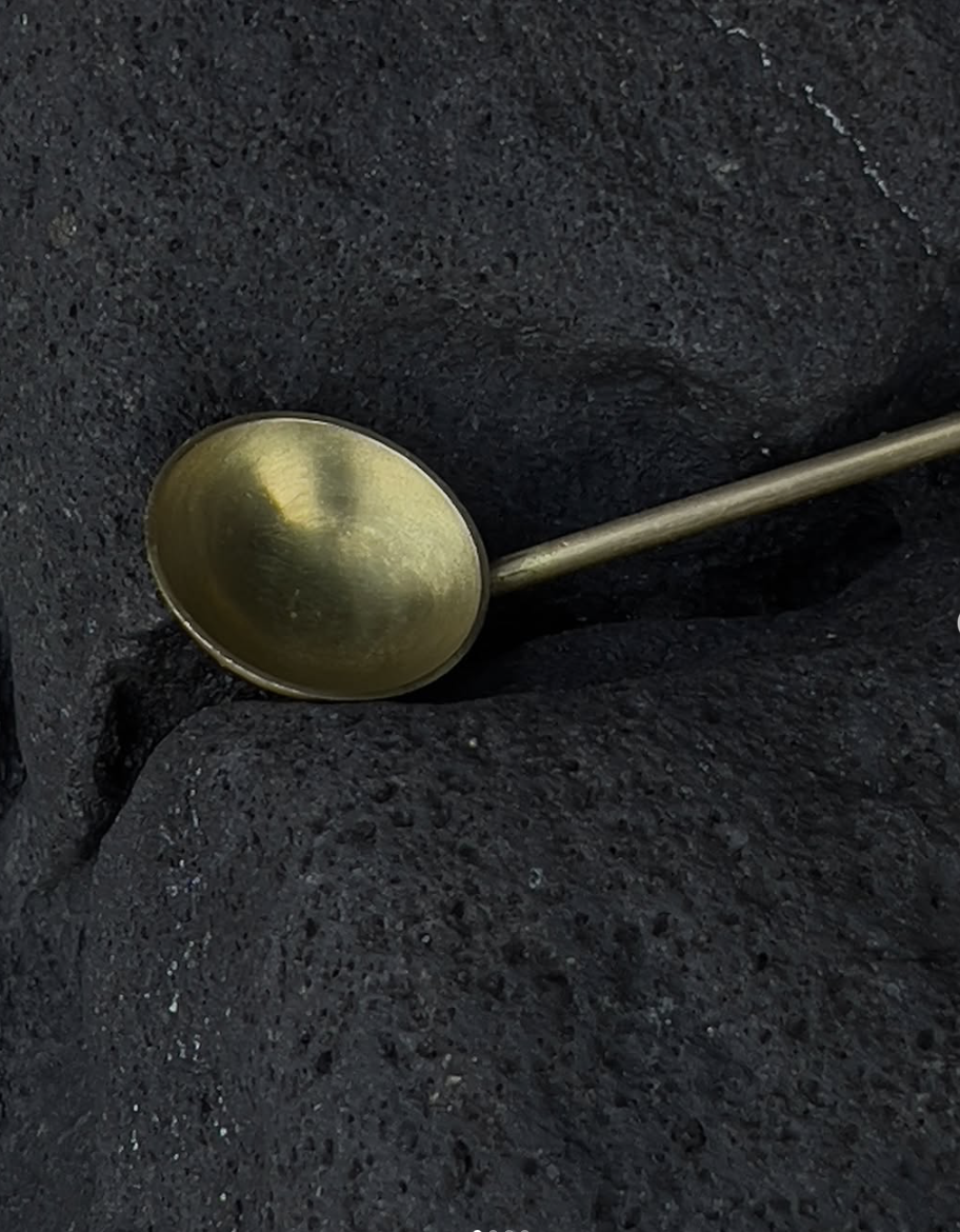 Mineralia homeware: close-up of a brass ladle on black rock