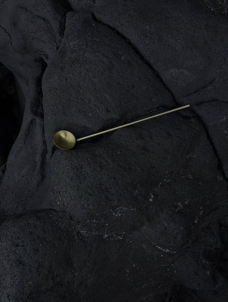 Mineralia homeware: long-handled brass spoon on black volcanic rock