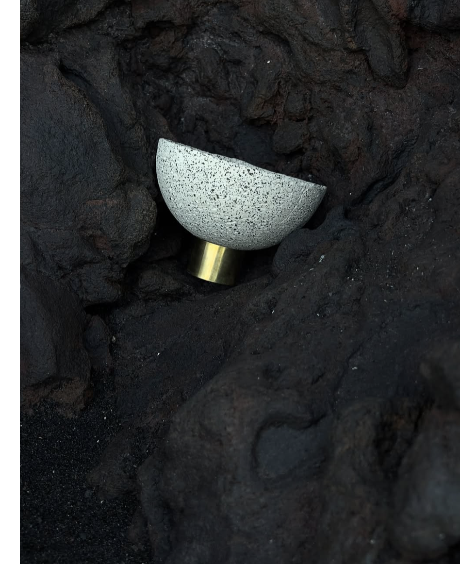 Mineralia homeware: speckled ceramic bowl on a brass foot among dark rocks