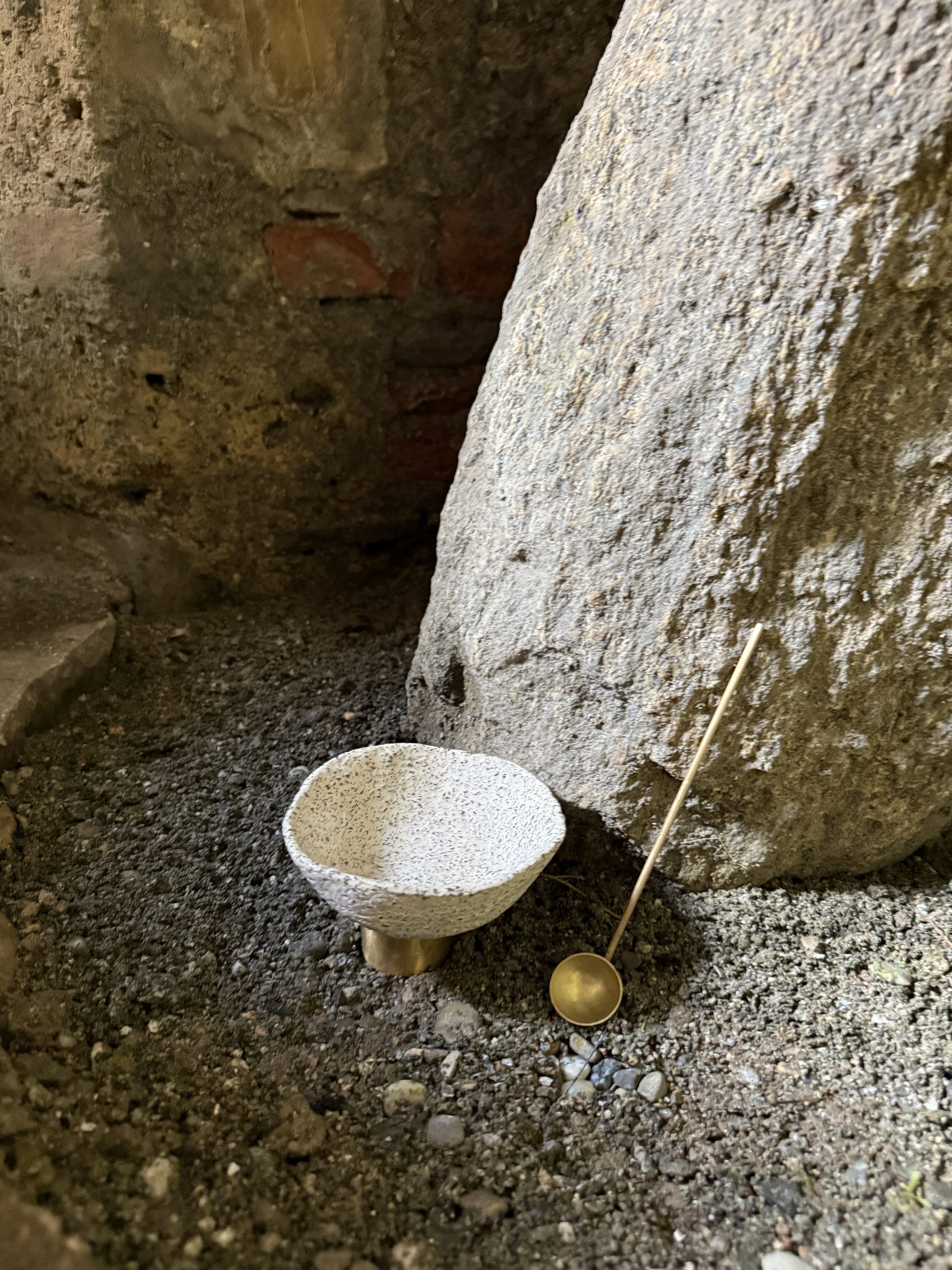 Mineralia homeware: speckled ceramic bowl and brass ladle beside a boulder