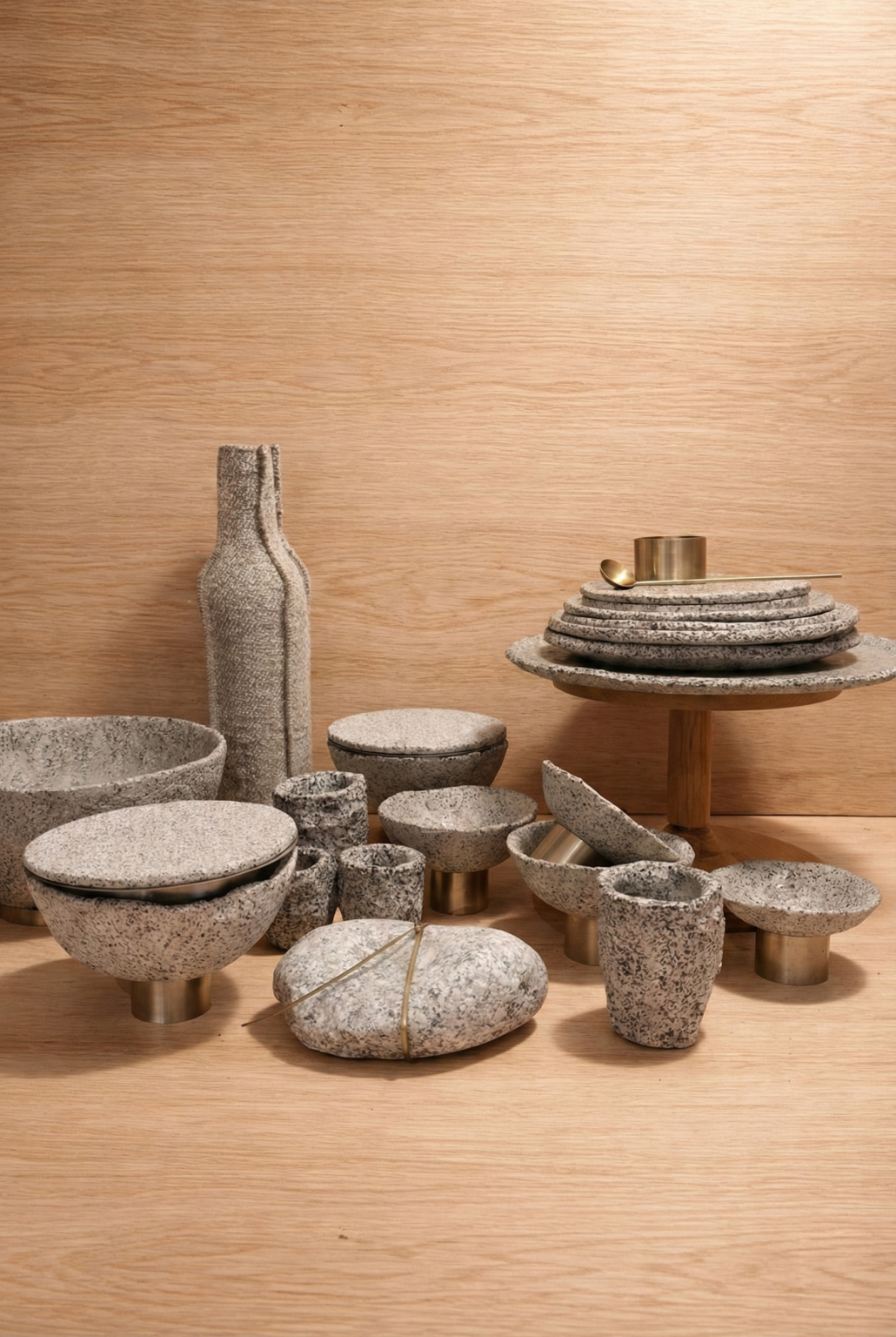 Mineralia homeware: speckled ceramic vases, bowls and plates on stands against oak