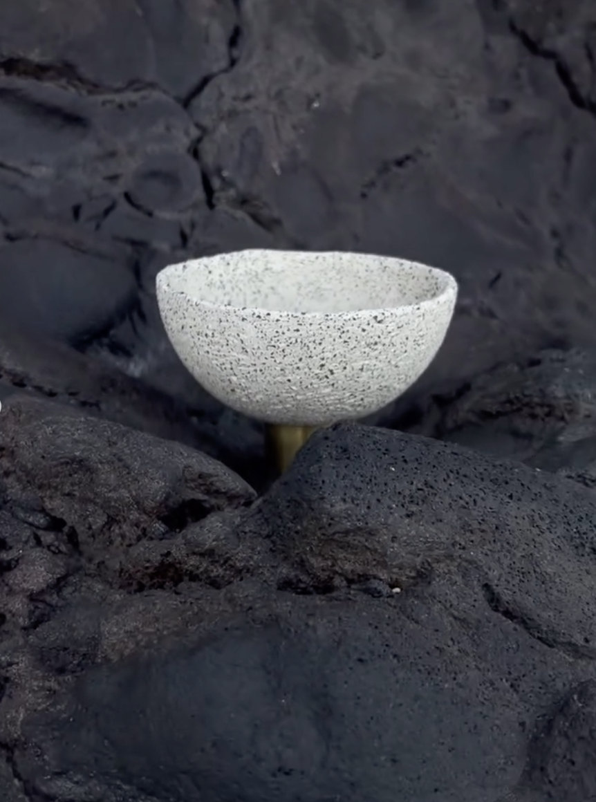 Mineralia homeware: speckled white bowl on a brass stem against black stone