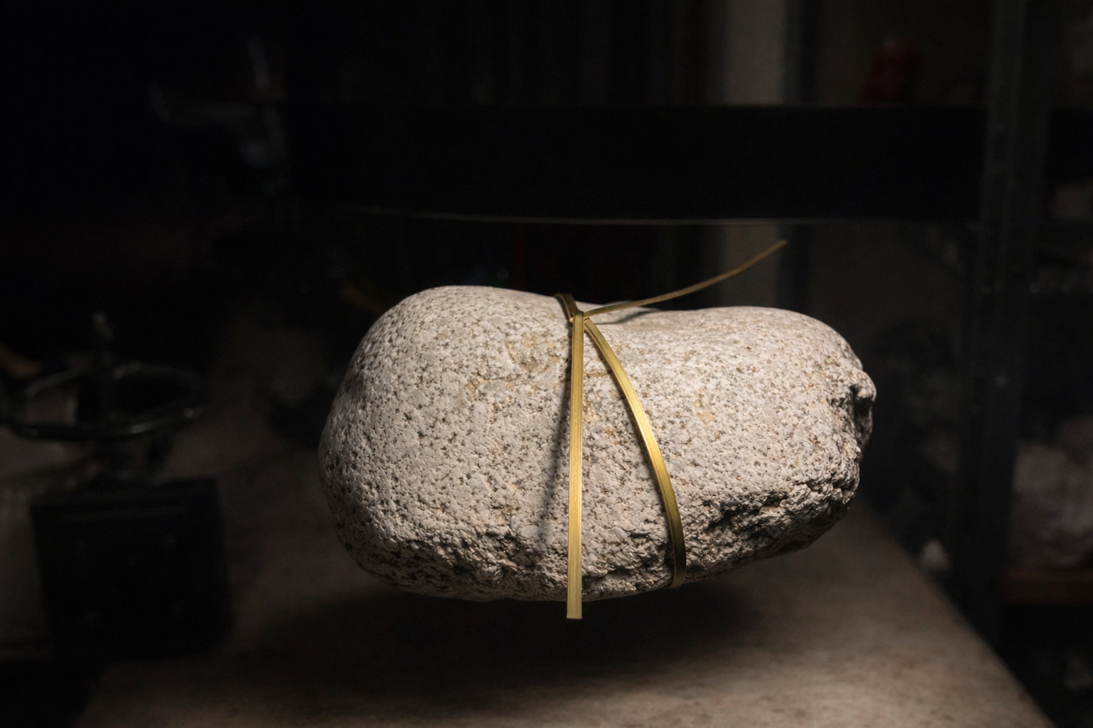 Mineralia homeware: stone bound with brass wire on a dark surface