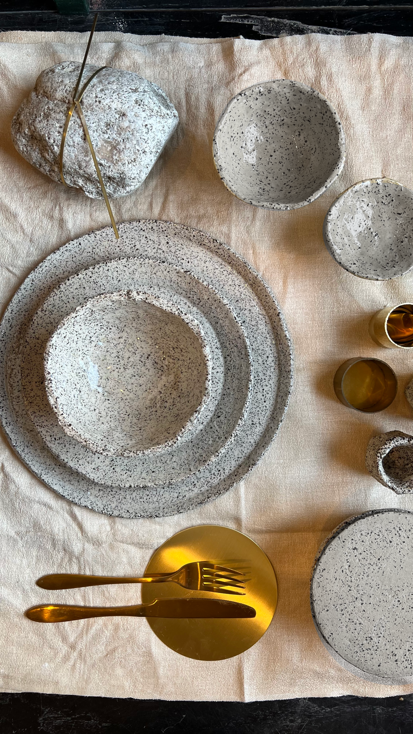 Mineralia homeware: table set with speckled ceramic plates, bowls and brass cutlery