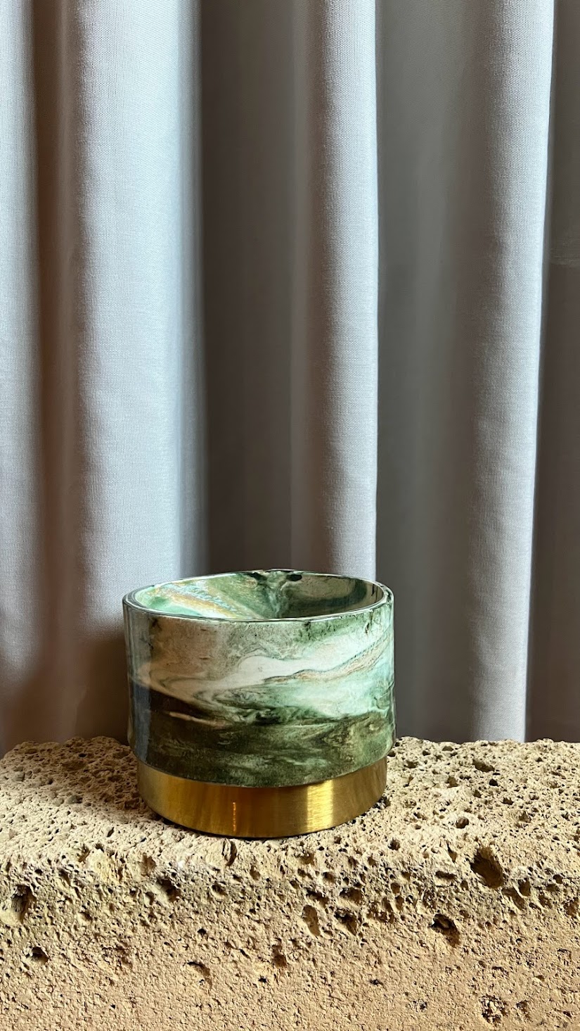 Panta Rei vase collection: green marbled vessel with a brass base on travertine