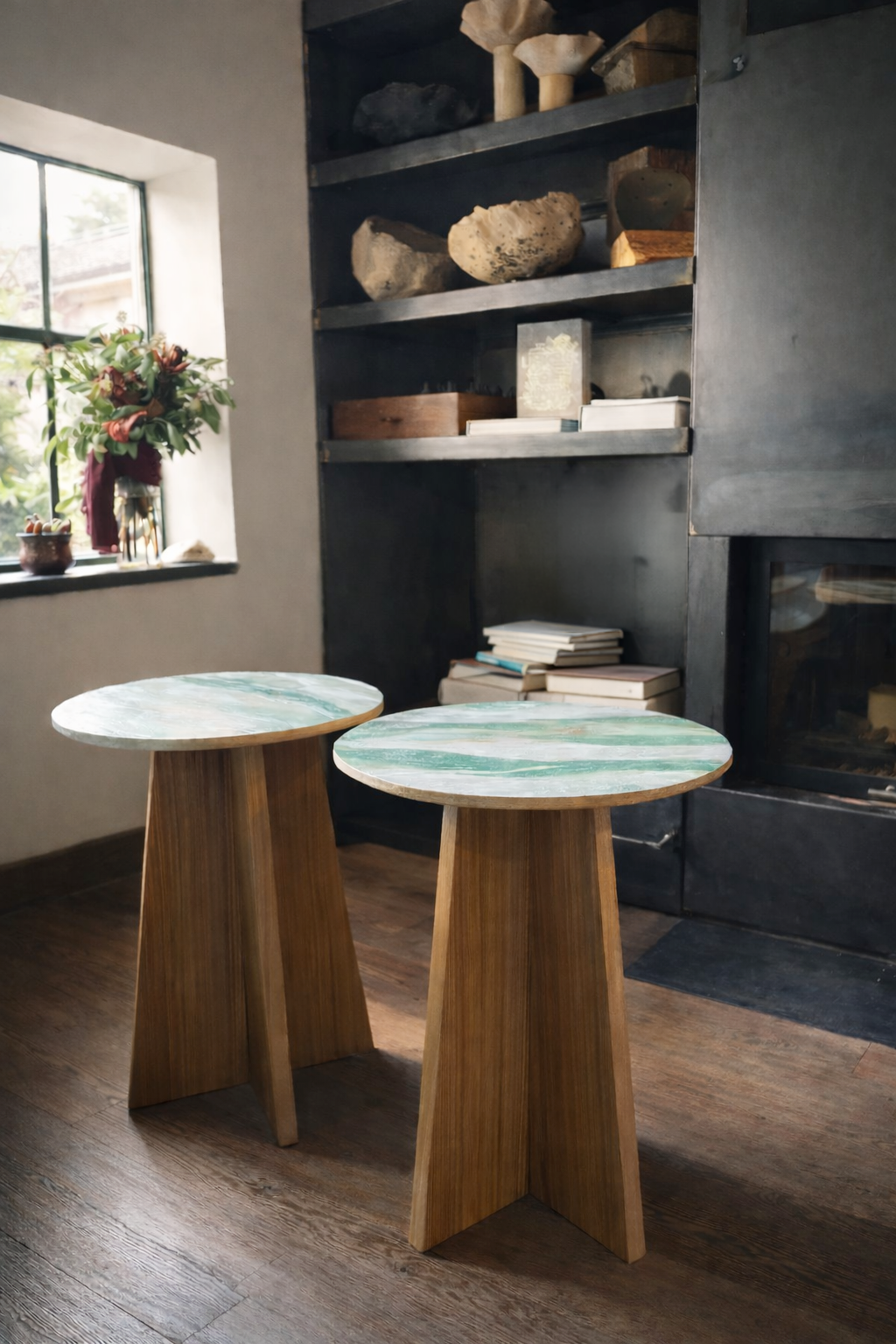 Panta Rei tables: two round ceramic-top tables on oak cross bases in a dark interior