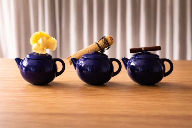Teapot ceramic project: three cobalt blue teapots on a wooden table