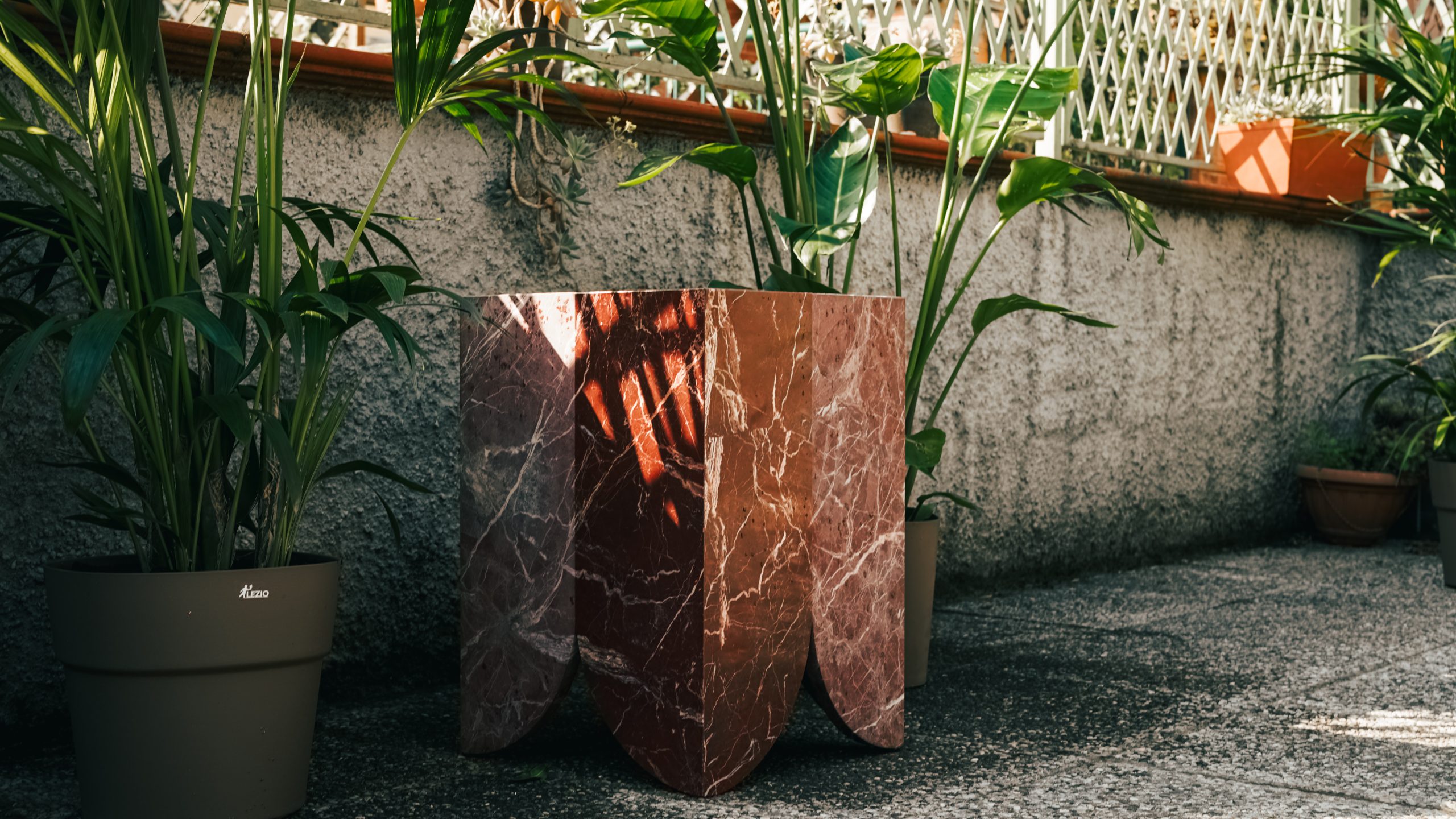 Atlas collection: red veined marble side table with scalloped base on a planted terrace