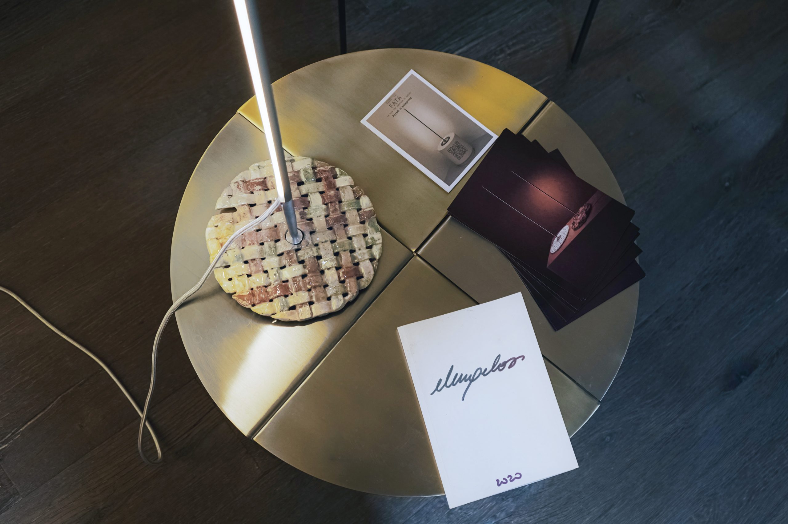 FATA lamp special edition: woven lamp base on a round brass table with cards