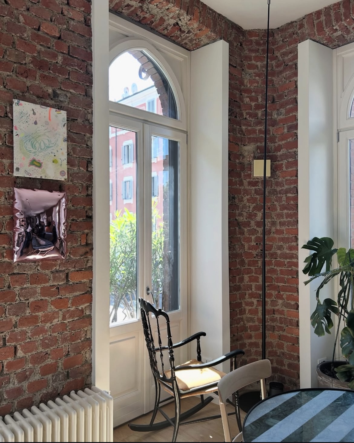 Elena Pelosi Studio: angolo in mattoni a vista con finestra ad arco e sedia antica