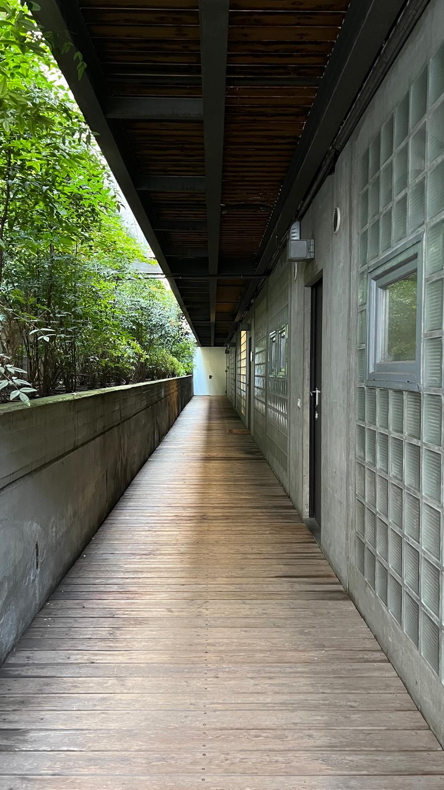 The Brutalist Grid: covered walkway along a glass block wall and a planted edge