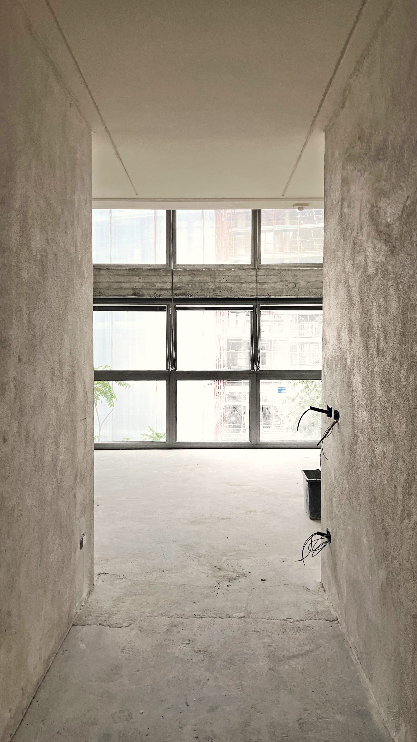The Brutalist Grid: raw plaster passage towards a steel-framed window during works
