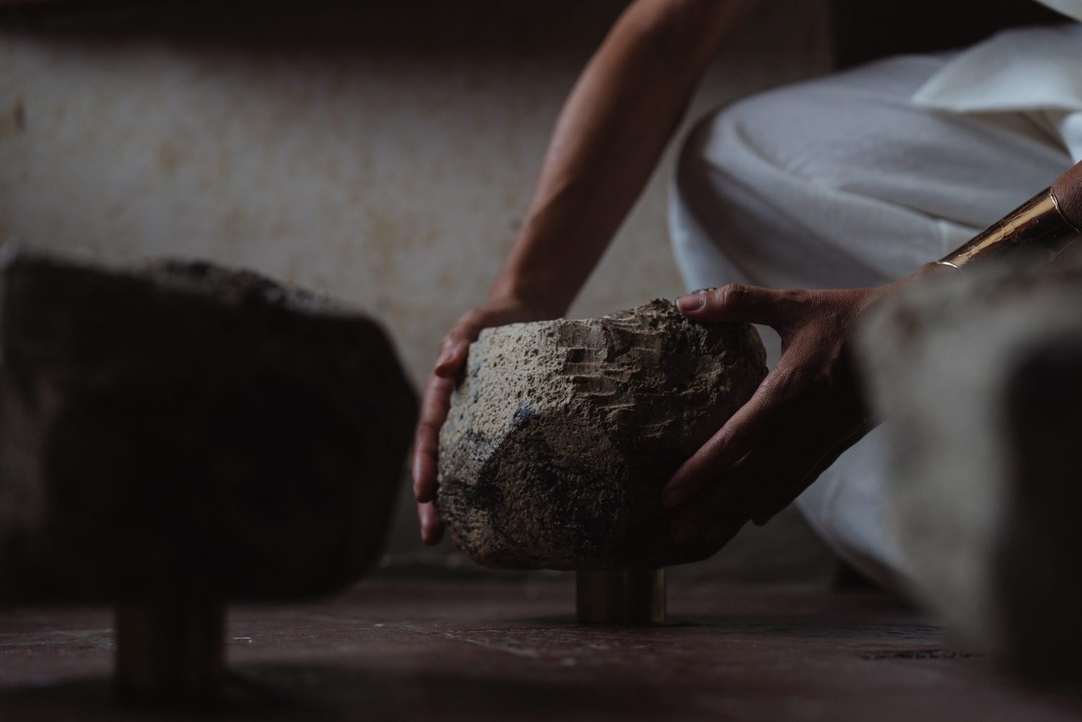 Spatial threshold research: hands placing a ceramic stone in low light