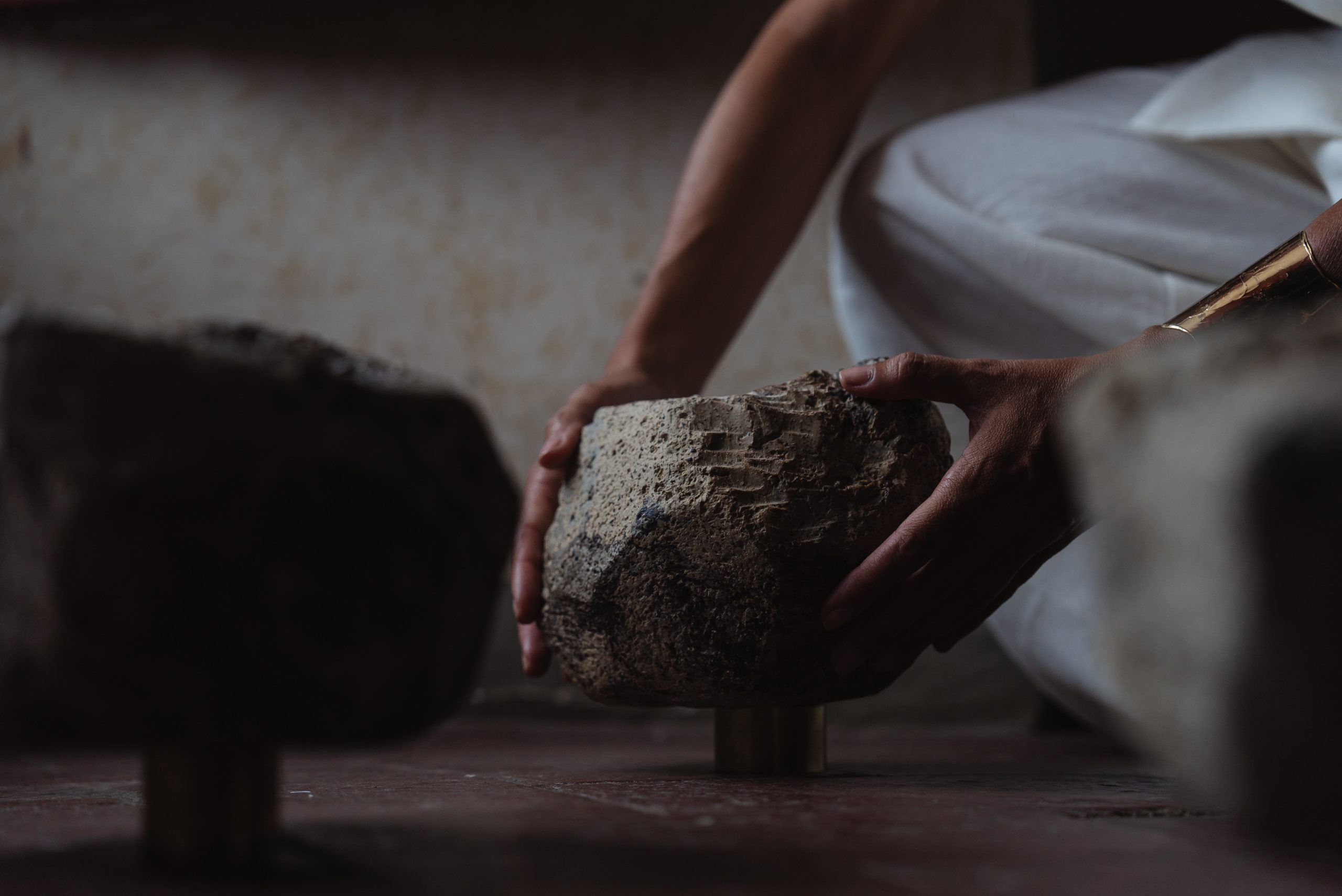 Spatial threshold research: hands placing a ceramic stone in low light