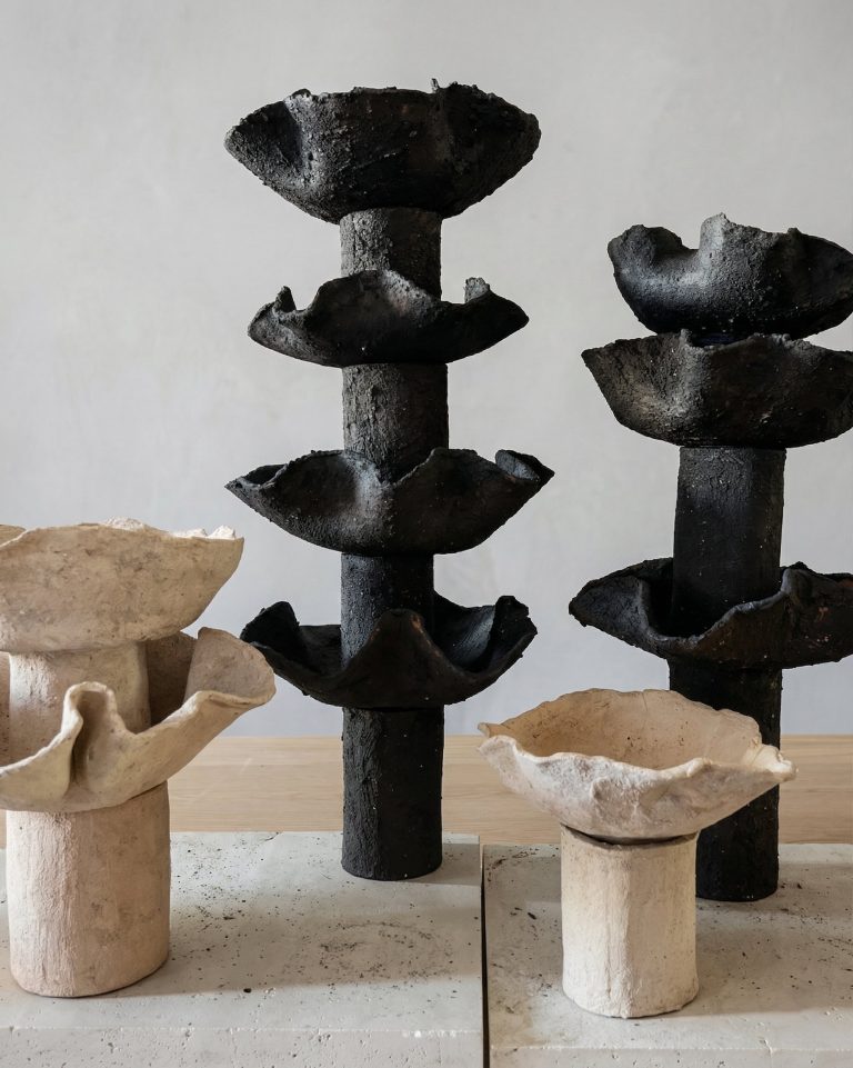 Delayed Matter by Elena Pelosi: dark stacked ceramic columns and pale ceramic bowls with cracked, mineral surfaces